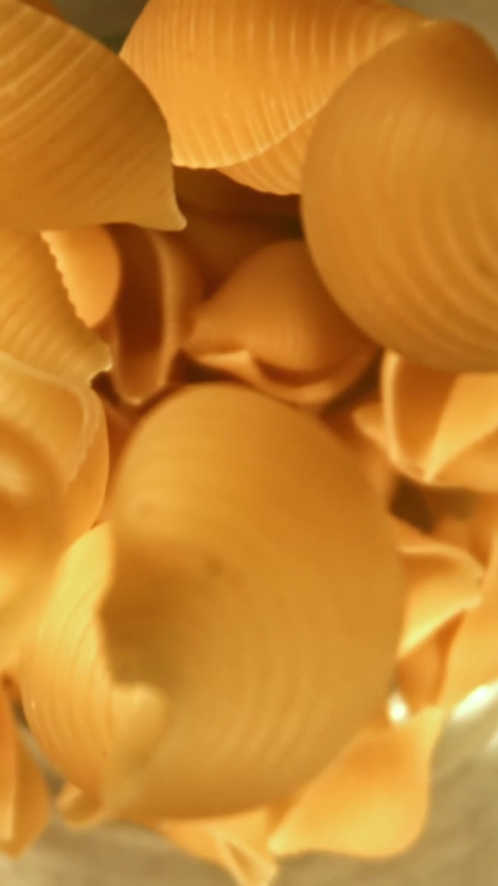 Conchiglie di pasta secche che cadono in un contenitore