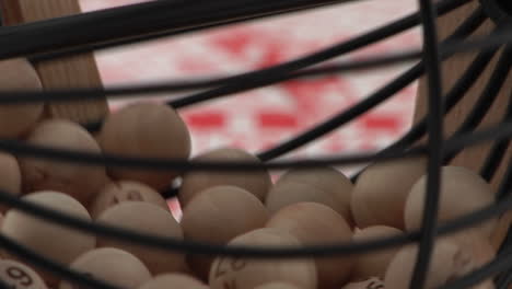 a cage of bingo balls spins in front of bingo cards