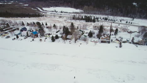 Drones-Voladores-Sobre-Casas-Y-Un-Lago-Congelado-Durante-El-Invierno-En-Canadá