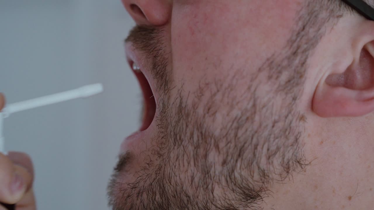 Close-up de um homem aplicando spray oral na boca. Conceito de cuidado da garganta, tratamento de mau hálito, rotina de higiene, saúde e bem-estar pessoal