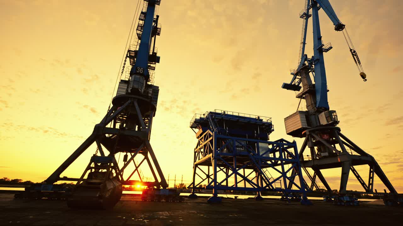 Cinematic shot of port cranes at sunset over Riga's industrial harbor, Latvia