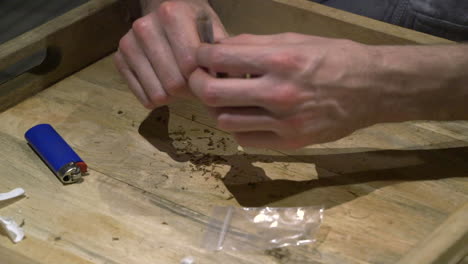 a man brings the final touch to his finished joint and is ready for a smoke