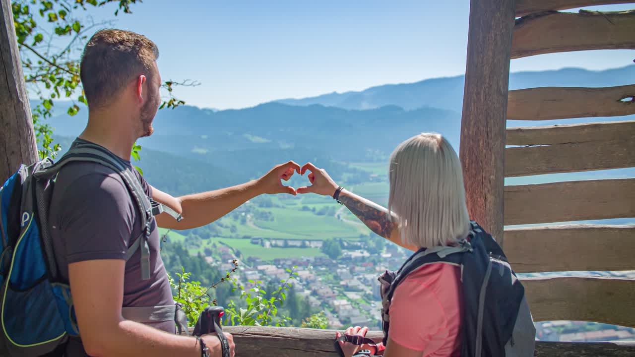couple of hikers at viewing point making heart sign. Valentine's day concept