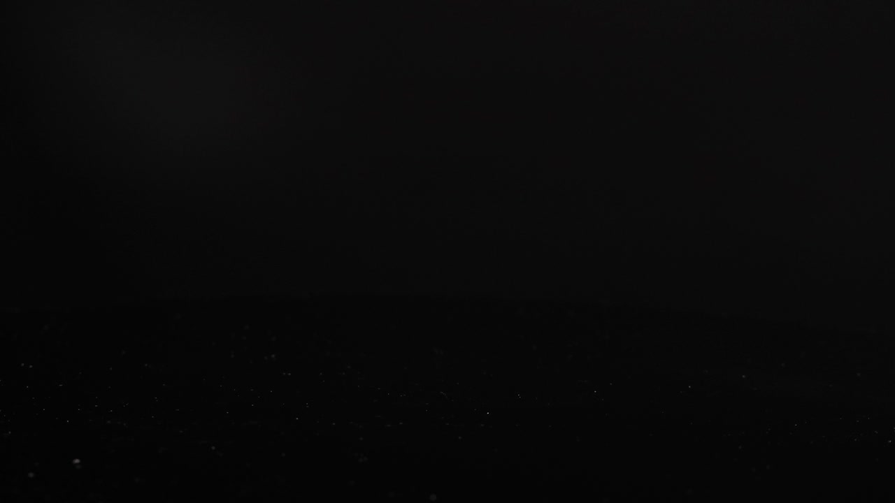 Rosemary sprigs drop onto a glossy black surface, creating a dynamic, aromatic visual with elegant reflections