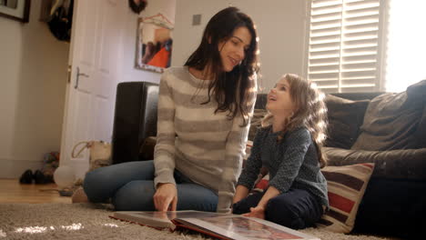 mother and daughter at home looking through photo album