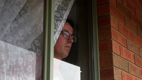 hombre blanco mira por la ventana