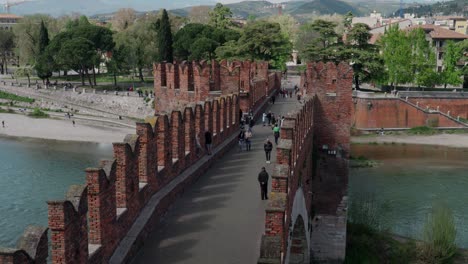 tourists crossing the bridge of castelvecchio museum in verona, italy