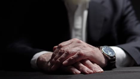 closeup hands male official sitting at dark office, shadow business, criminality