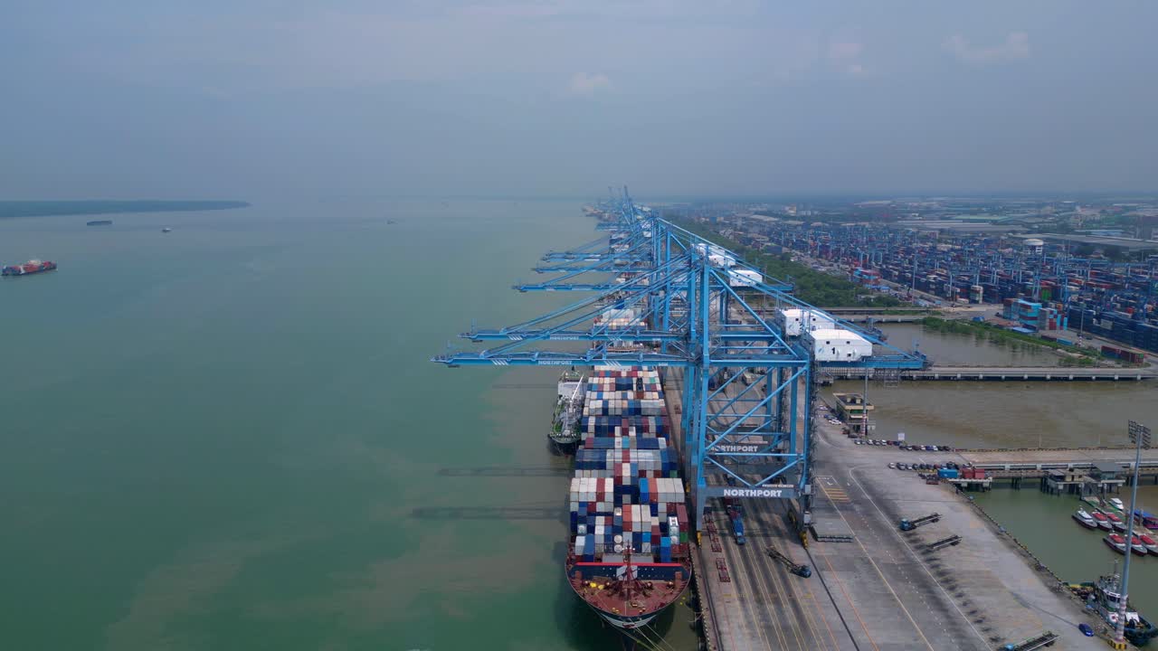 large container ship docked at Northport terminal with gantry cranes, illustrating global logistics and maritime trade. Spectacular aerial view panorama overview drone