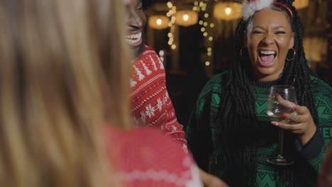 tracking shot pulling away from small group of friends celebrating christmas at a bar