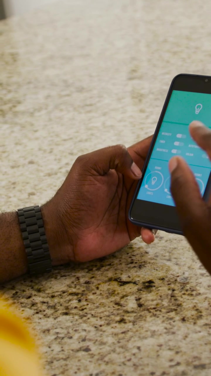 Vertical video: App open man tapping lighting dials to set lights at home counter, yellow sleeve