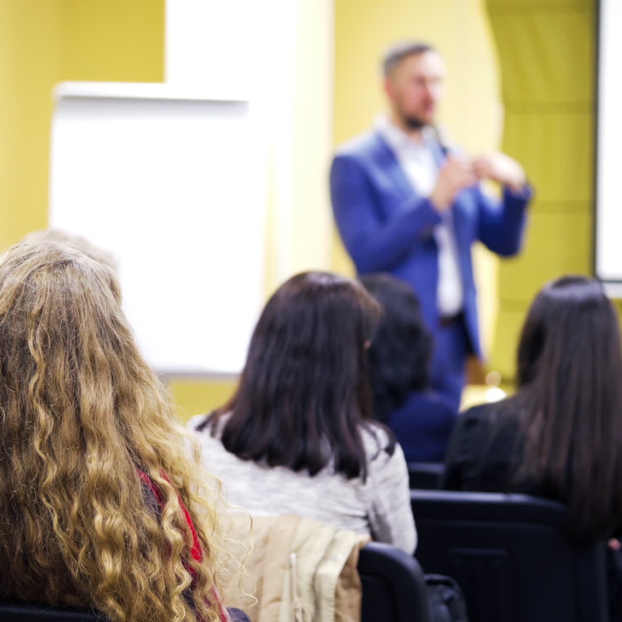 Audience listens to the speaker at the conference hall. People are sitting in the auditorium and listening the lecture at business forum.