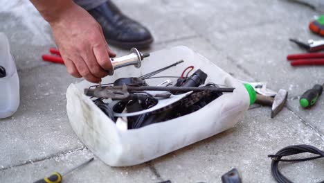 caucasian male mechanic kneeling on ground looking inside white tool box, close up pan