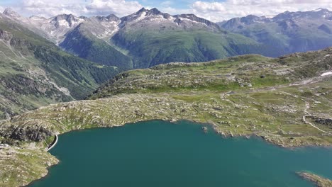 un dron vuela sobre un lago de montaña con una impresionante cordillera en el fondo en grimselpass, suiza