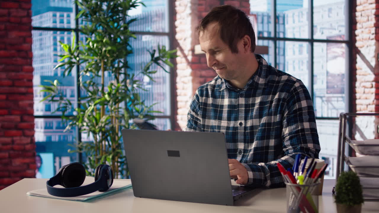 Man seated at home office desk using computer, checking emails