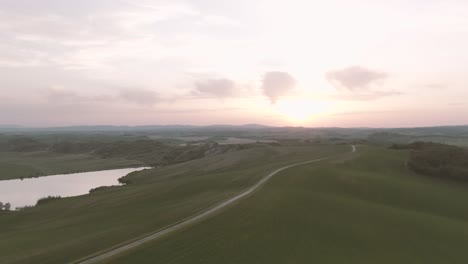 una foto de un dron de una puesta de sol sobre las ondulantes colinas de toscana