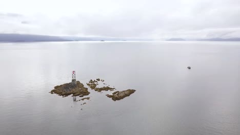 Wide-Orbit-of-Vanderbilt-Reef-with-Navigation-Beacon-and-Diver's-Boat-Backlit-by-Sunset-and-Alaskan-Mountain-Range,-Inside-Passage