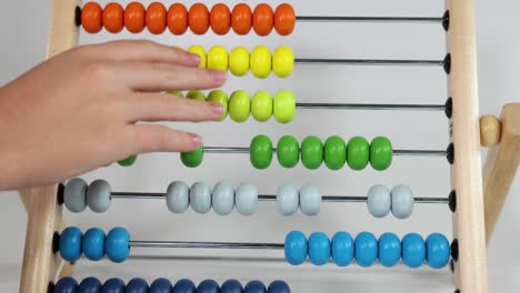 hands moving beads on a colorful abacus