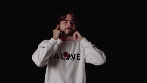 trendy young man covering ears with fingers, wide, black background