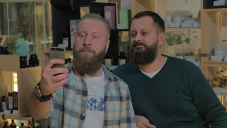 two bearded men taking mobile selfie indoor