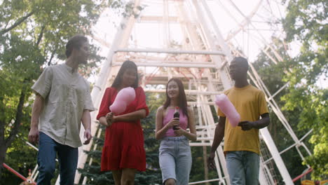 four people talking and walking in a park