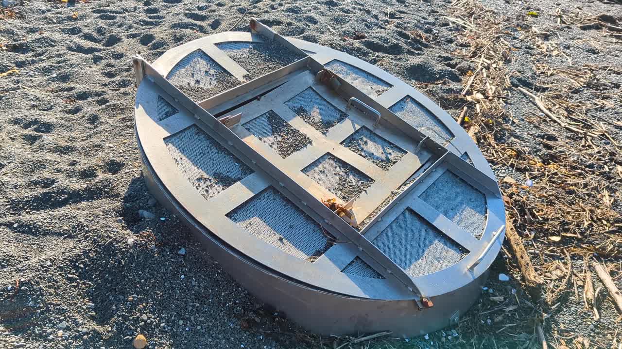Mysterious metal tunnel bunker hatch door, locked safe and secure, found on sandy beach
