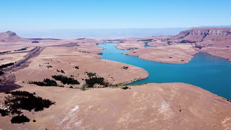 toma aérea de drones del pintoresco paisaje montañoso y praderas secas de sabana que rodean las hermosas aguas azules de la presa driekloof, estado libre, sudáfrica