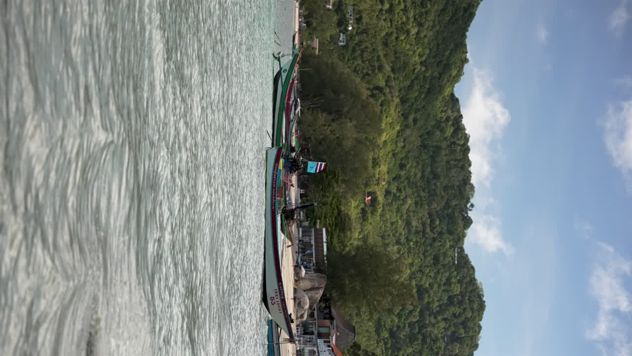 Tropical beach scene featuring calm turquoise waters, boats anchored along the shore. vertical video, slow motions shot