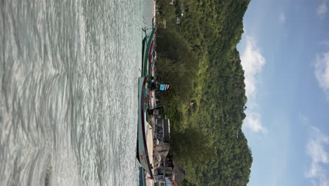 tropical beach scene featuring calm turquoise waters, boats anchored along the shore. vertical video, slow motions shot