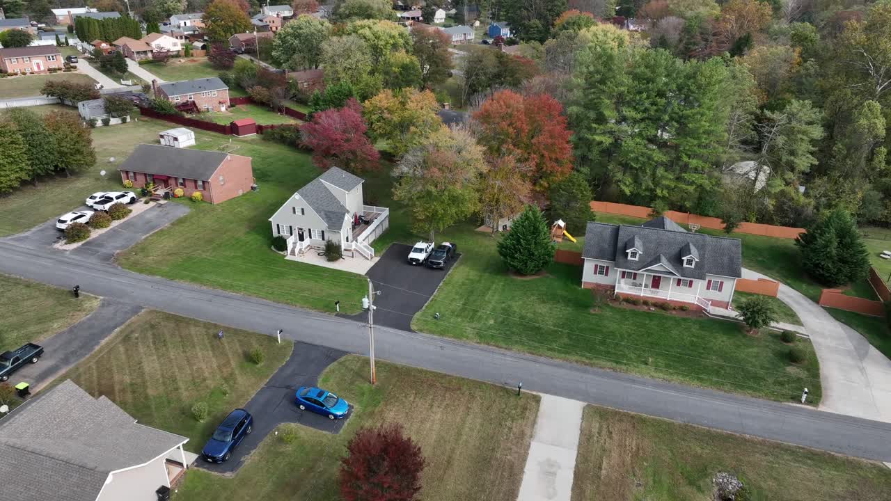 Peaceful suburb neighborhood in American town. Single family houses and colored trees in garden. Parking vehicles on driveway. Aerial view. Sunny das in autumn season