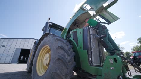 farmer mechanic repairing tractor. open tractor hood, engine. repair agricultural technology