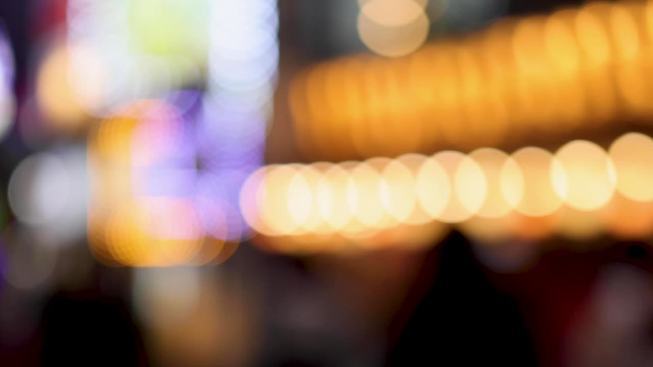 Luci dorate e bianche, vivaci e fuori fuoco, creano una calda atmosfera astratta in una notte urbana.