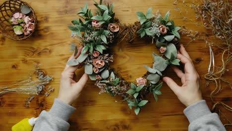 hands puts spring floral wreath on table.