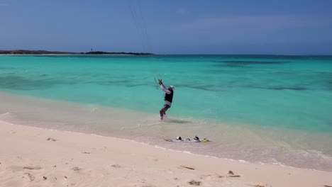 man arrive shore beach after kitesurf, hands steering bar and drop board on white sand