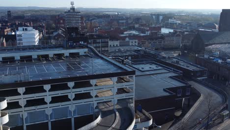 Overhead-aerial-view-above-city-multi-storey-car-park-quiet-British-urban-public-streets-at-sunrise-right-orbit