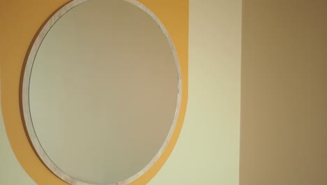 round wooden framed mirror on a two-tone wall