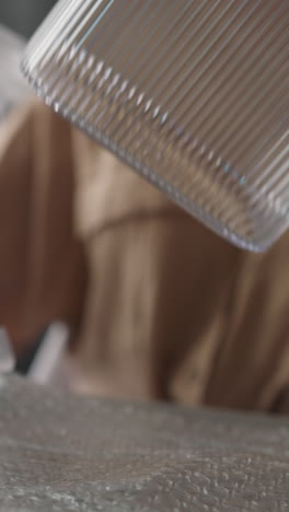 young woman removes protective film from plastic container for storing loose food products. female removes lid examining kitchenware at home closeup