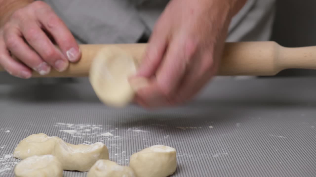 Primo piano delle mani di uno chef uomo che stende l'impasto con un mattarello
