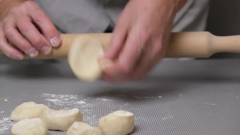primer plano de las manos de un chef masculino rodando la masa con un rodillo.