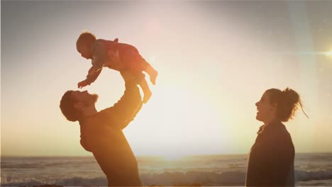 animation of glowing spots over caucasian parents with baby by the sea