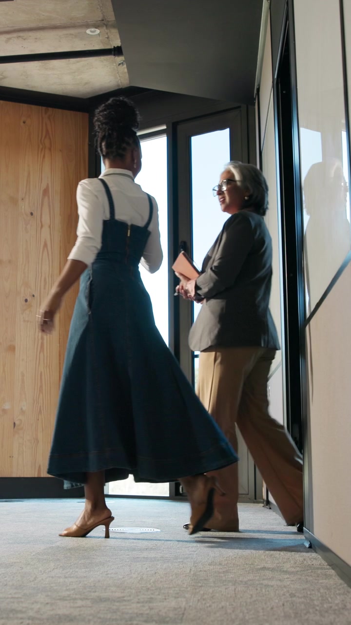 Gruppo eterogeneo di professionisti che cammina lungo un corridoio di un ufficio moderno