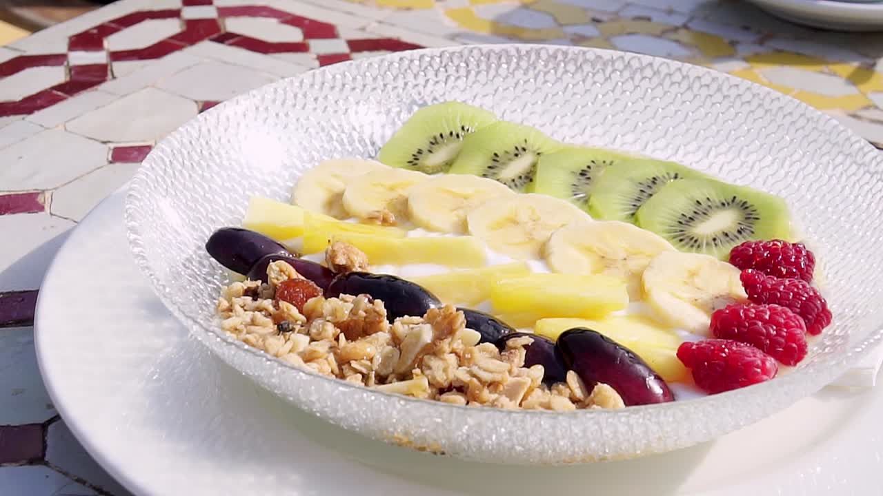 晴れた日の屋外で、フルーツとナッツを添えた美味しくてヘルシーな朝食プレート。