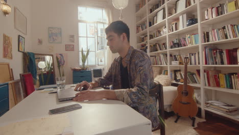 young man opening laptop and working online in cozy room