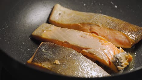 salmón frito con mantequilla en una sartén negra. bucle. clip sin costuras. menú saludable con bajas calorías.