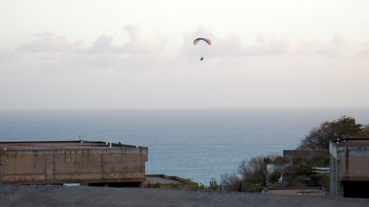 Handheld shot of a paraglider enjoying a scenic flight over the dramatic cliffs of Bali