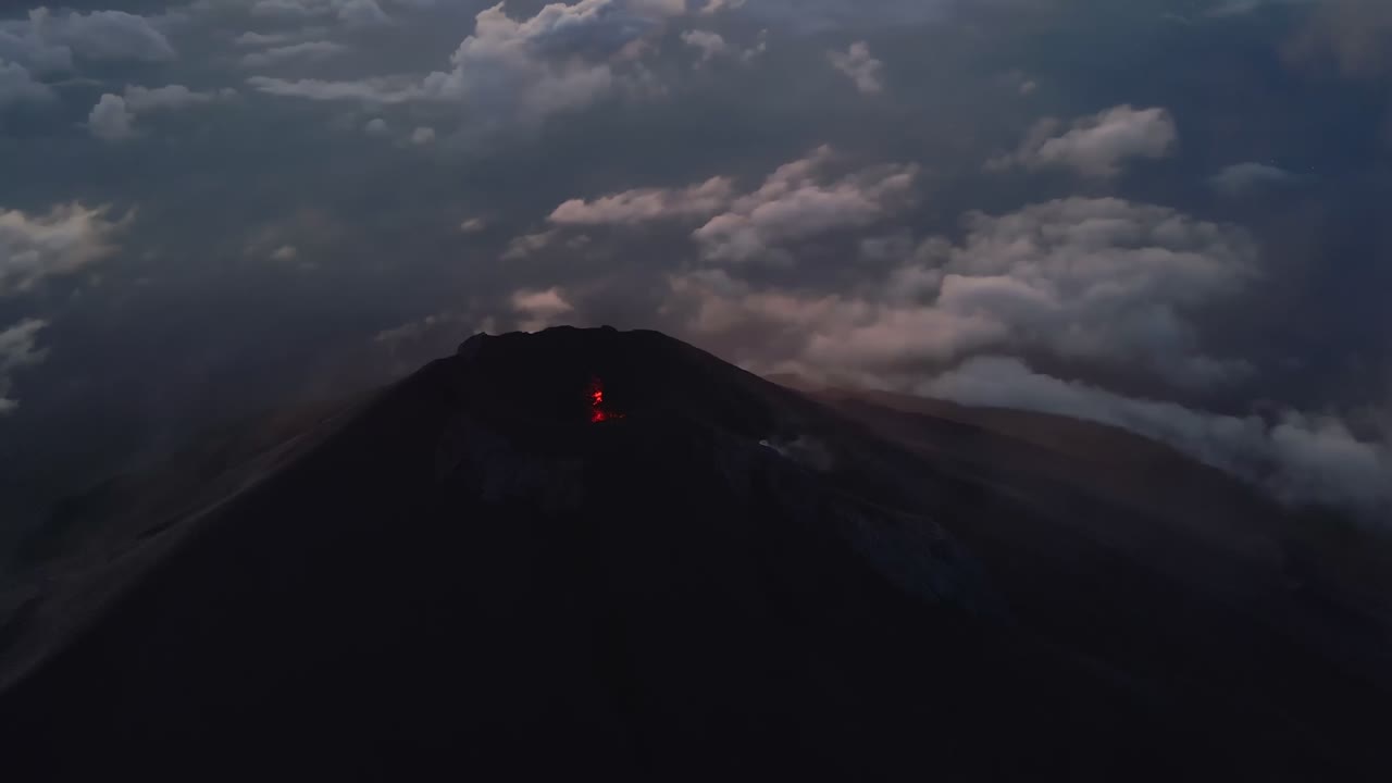 vista aérea cinematográfica del cráter lleno de lava del volcán fuego en la hora azul, guatemala