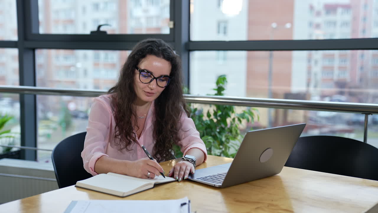 Woman working on laptop and notebook in office