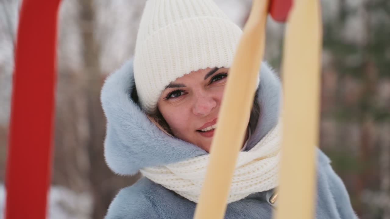 Madre in un parco giochi innevato, guarda il figlio fuori campo, avvolta in berretto e sciarpa, sbircia dietro la struttura dell'altalena con sguardo contemplativo, luce invernale soffusa, sfondo di pini sfocati, tenera genitorialità.