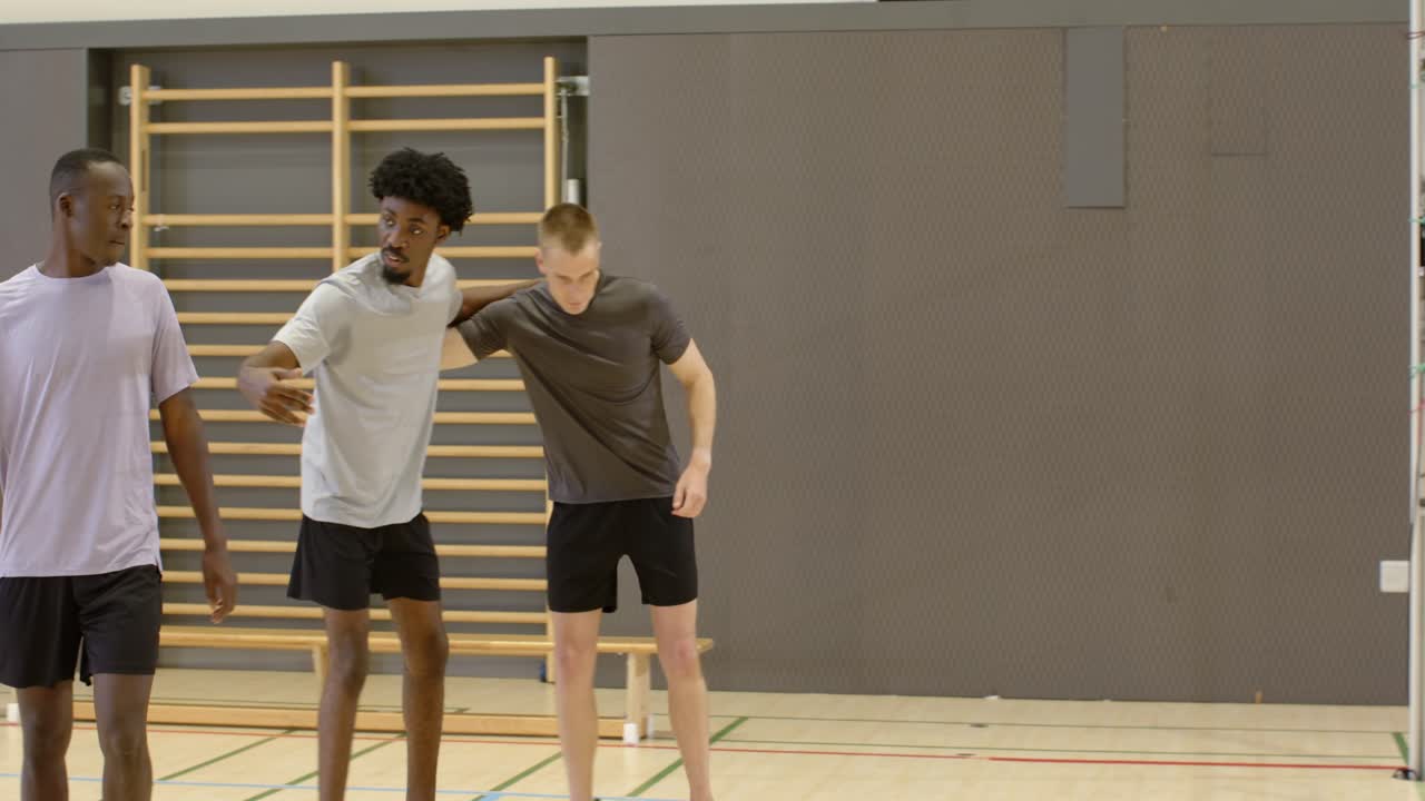 Forskellige mandlige spillere roterer efter et point ved nettet i sportshallen, sender bolden rundt, klapper hinanden på ryggen og fejrer.