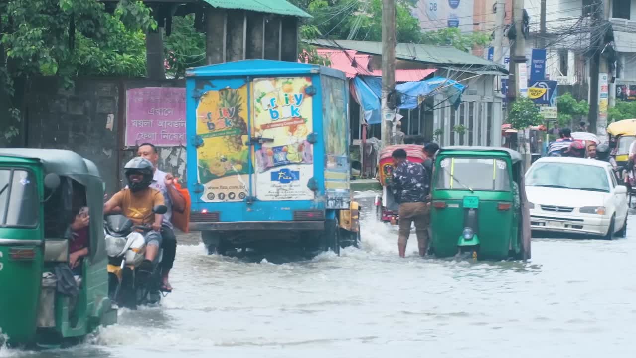 Flooded downtown roads in Bangladesh. vehicles and rickshaw taxi bikes struggling to drive on